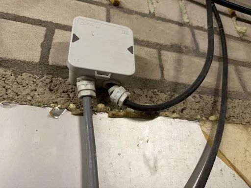 Lasdoos met open invoer aan een stalmuur