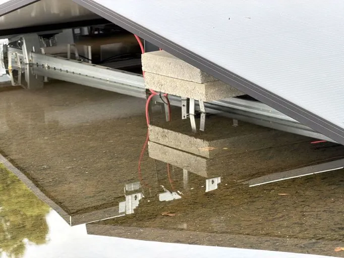 Zonnepanelen op een plat dak met water en stoeptegels als ballast